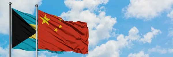 Багамские острова и флаг Китая, размахивающие ветром против белого облачно-синего неба вместе. Концепция дипломатии, международные отношения . — стоковое фото