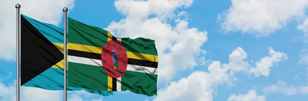 Bandera de Bahamas y Dominica ondeando en el viento contra el cielo azul nublado blanco juntos. Concepto diplomático, relaciones internacionales . — Foto de Stock