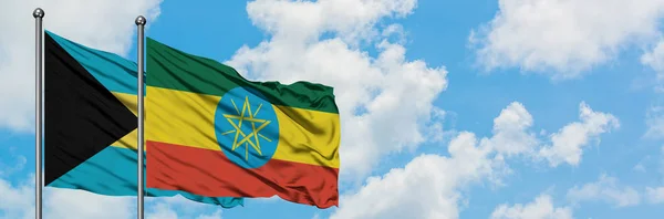 一緒に白い曇り青い空に対して風に手を振るバハマとエチオピアの旗。外交概念、国際関係. — ストック写真