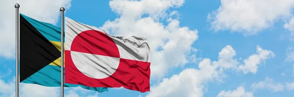 Bahamas et le Groenland drapeau agitant dans le vent contre ciel bleu nuageux blanc ensemble. Concept de diplomatie, relations internationales . — Photo
