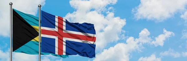 Bandera de Bahamas e Islandia ondeando en el viento contra el cielo azul nublado blanco juntos. Concepto diplomático, relaciones internacionales . — Foto de Stock
