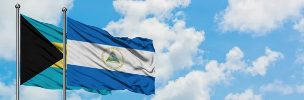 Bahamas and Nicaragua flag waving in the wind against white cloudy blue sky together. Diplomacy concept, international relations.