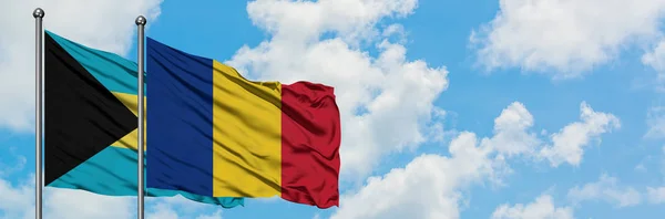Bandera de Bahamas y Rumania ondeando en el viento contra el cielo azul nublado blanco juntos. Concepto diplomático, relaciones internacionales . — Foto de Stock