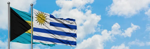Μπαχάμες και τη σημαία της Ουρουγουάης που κουνώντας τον άνεμο εναντίον του λευκού νεφελώδες γαλάζιο του ουρανού μαζί. Φιλοσοφία της διπλωματίας, διεθνείς σχέσεις. — Φωτογραφία Αρχείου