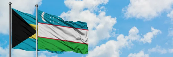 Bahamas e la bandiera dell'Uzbekistan sventolano insieme nel vento contro il bianco cielo blu nuvoloso. Concetto di diplomazia, relazioni internazionali . — Foto Stock