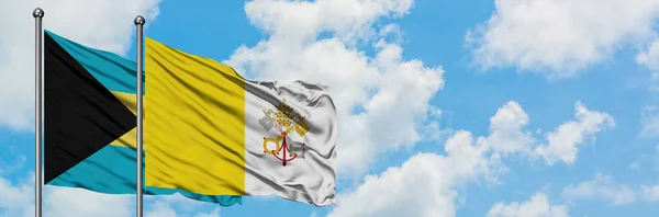 Bahamas en Vaticaanstad vlag zwaaien in de wind tegen witte bewolkte blauwe hemel samen. Diplomatie concept, internationale betrekkingen. — Stockfoto