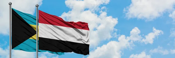 Bandera de Bahamas y Yemen ondeando en el viento contra el cielo azul nublado blanco juntos. Concepto diplomático, relaciones internacionales . — Foto de Stock