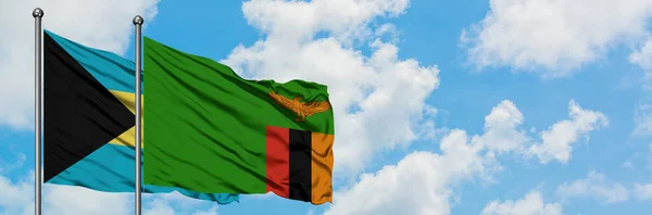 Bahamas and Zambia flag waving in the wind against white cloudy blue sky together. Diplomacy concept, international relations. — Stock Photo, Image