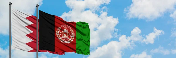 Bandera de Bahréin y Afganistán ondeando en el viento contra el cielo azul nublado blanco juntos. Concepto diplomático, relaciones internacionales . — Foto de Stock