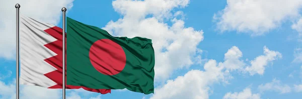 Bandera de Bahréin y Bangladesh ondeando en el viento contra el cielo azul nublado blanco juntos. Concepto diplomático, relaciones internacionales . — Foto de Stock