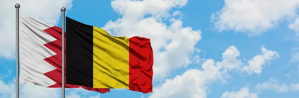 Bandera de Bahréin y Bélgica ondeando en el viento contra el cielo azul nublado blanco juntos. Concepto diplomático, relaciones internacionales . — Foto de Stock