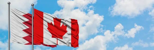 Bandera de Bahréin y Canadá ondeando en el viento contra el cielo azul nublado blanco juntos. Concepto diplomático, relaciones internacionales . — Foto de Stock
