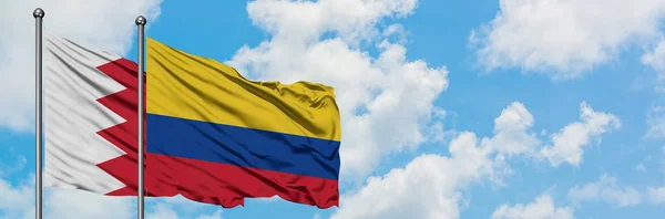 Bandera de Bahréin y Colombia ondeando en el viento contra el cielo azul nublado blanco juntos. Concepto diplomático, relaciones internacionales . — Foto de Stock