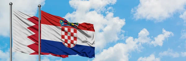 Bandera de Bahréin y Croacia ondeando en el viento contra el cielo azul nublado blanco juntos. Concepto diplomático, relaciones internacionales . — Foto de Stock