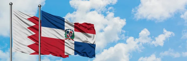 一緒に白い曇り青い空に対して風に手を振るバーレーンとドミニカ共和国の旗。外交概念、国際関係. — ストック写真