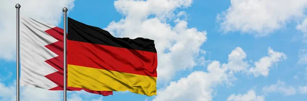 Bahrein és Németország zászló integetett a szél ellen, fehér felhős kék ég együtt. Diplomáciai koncepció, nemzetközi kapcsolatok. — Stock Fotó
