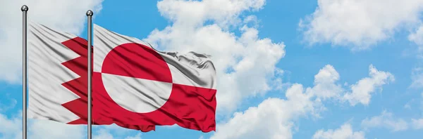 Drapeau du Bahreïn et du Groenland agitant dans le vent contre le ciel bleu nuageux blanc ensemble. Concept de diplomatie, relations internationales . — Photo