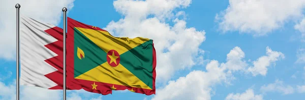 Bandera de Bahréin y Granada ondeando en el viento contra el cielo azul nublado blanco juntos. Concepto diplomático, relaciones internacionales . — Foto de Stock