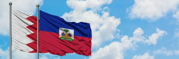 Bahreyn ve Haiti bayrağı birlikte beyaz bulutlu mavi gökyüzüne karşı rüzgarda sallayarak. Diplomasi kavramı, uluslararası ilişkiler. — Stok fotoğraf