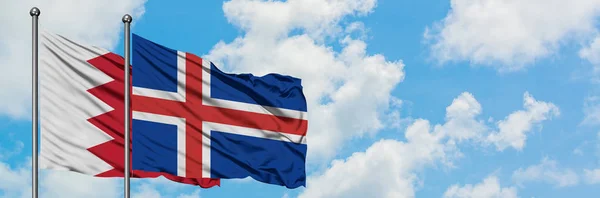 Bandera de Bahréin e Islandia ondeando en el viento contra el cielo azul nublado blanco juntos. Concepto diplomático, relaciones internacionales . — Foto de Stock
