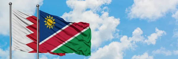Bahreïn et la Namibie drapeau agitant dans le vent contre ciel bleu nuageux blanc ensemble. Concept de diplomatie, relations internationales . — Photo