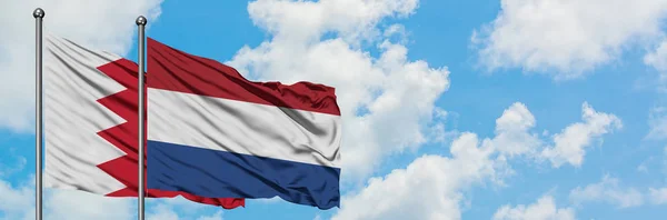 Бахрейн і Нідерланди прапор розмахуючи в вітру проти білого хмарного синього неба разом. Концепція дипломатії, міжнародні відносини. — стокове фото