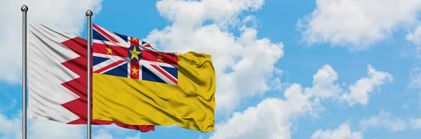 Bahrajn i Niue flaga machając w wiatr przed białym zachmurzone błękitne niebo razem. Koncepcja dyplomacji, stosunki międzynarodowe. — Zdjęcie stockowe