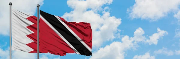 Bahreyn ve Trinidad ve Tobago bayrağı birlikte beyaz bulutlu mavi gökyüzüne karşı rüzgarda sallayarak. Diplomasi kavramı, uluslararası ilişkiler. — Stok fotoğraf