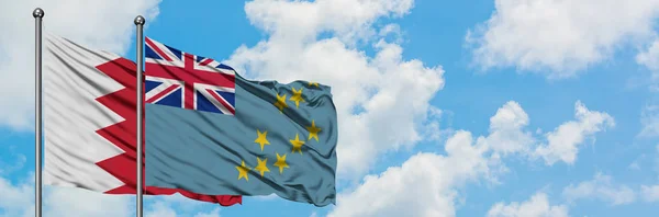 Bandera de Bahréin y Tuvalu ondeando en el viento contra el cielo azul nublado blanco juntos. Concepto diplomático, relaciones internacionales . — Foto de Stock