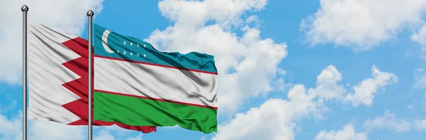 Bahreyn ve Özbekistan bayrağı birlikte beyaz bulutlu mavi gökyüzüne karşı rüzgarsal sallayarak. Diplomasi kavramı, uluslararası ilişkiler. — Stok fotoğraf