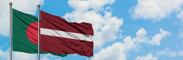 Drapeau du Bangladesh et de la Lettonie agitant dans le vent contre ciel bleu nuageux blanc ensemble. Concept de diplomatie, relations internationales . — Photo