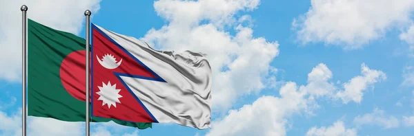 Bandera de Bangladesh y Nepal ondeando en el viento contra el cielo azul nublado blanco juntos. Concepto diplomático, relaciones internacionales . — Foto de Stock