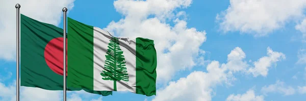 Bandera de Bangladesh y Norfolk Island ondeando en el viento contra el cielo azul nublado blanco juntos. Concepto diplomático, relaciones internacionales . — Foto de Stock