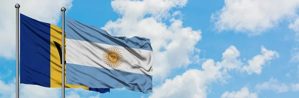 バルバドスとアルゼンチンの旗は、一緒に白い曇り青い空に対して風に手を振る。外交概念、国際関係. — ストック写真