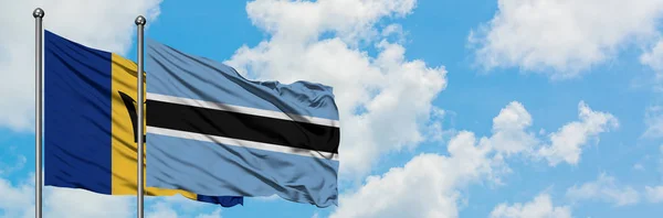 Barbados és Botswana zászló integetett a szél ellen, fehér felhős kék ég együtt. Diplomáciai koncepció, nemzetközi kapcsolatok. — Stock Fotó