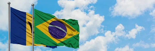Bandera de Barbados y Brasil ondeando en el viento contra el cielo azul nublado blanco juntos. Concepto diplomático, relaciones internacionales . — Foto de Stock