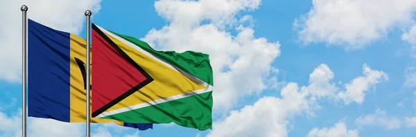 バルバドスとガイアナの旗は、一緒に白い曇った青い空に対して風に手を振る。外交概念、国際関係. — ストック写真
