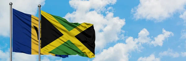 Bandera de Barbados y Jamaica ondeando en el viento contra el cielo azul nublado blanco juntos. Concepto diplomático, relaciones internacionales . —  Fotos de Stock