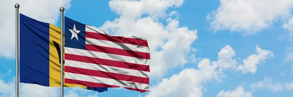 Barbados ve Liberya bayrağı birlikte beyaz bulutlu mavi gökyüzüne karşı rüzgarda sallayarak. Diplomasi kavramı, uluslararası ilişkiler. — Stok fotoğraf