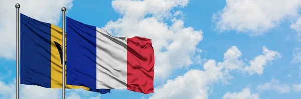 Barbade et drapeau de la Réunion agitant dans le vent contre ciel bleu nuageux blanc ensemble. Concept de diplomatie, relations internationales . — Photo