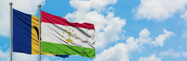 Bandera de Barbados y Tayikistán ondeando en el viento contra el cielo azul nublado blanco juntos. Concepto diplomático, relaciones internacionales . — Foto de Stock