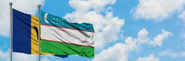 Bandera de Barbados y Uzbekistán ondeando en el viento contra el cielo azul nublado blanco juntos. Concepto diplomático, relaciones internacionales . — Foto de Stock