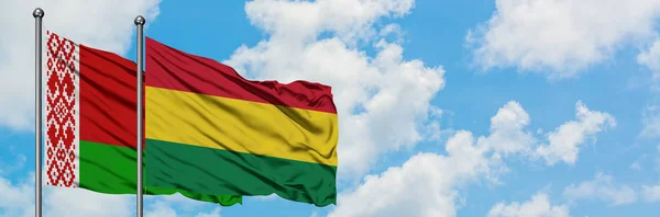 Bandera de Bielorrusia y Bolivia ondeando en el viento contra el cielo azul nublado blanco juntos. Concepto diplomático, relaciones internacionales . — Foto de Stock