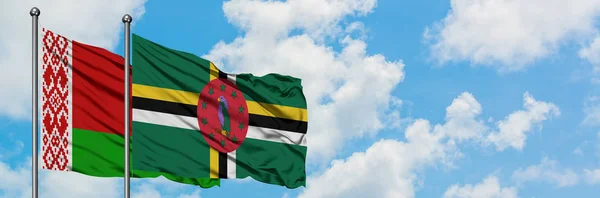 Bandera de Bielorrusia y Dominica ondeando en el viento contra el cielo azul nublado blanco juntos. Concepto diplomático, relaciones internacionales . — Foto de Stock