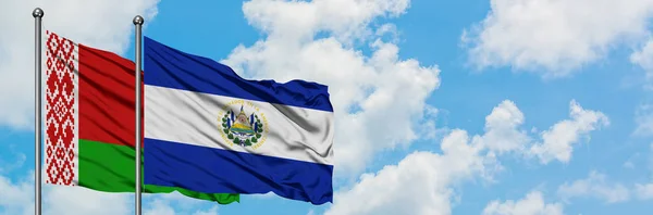 Bandera de Bielorrusia y El Salvador ondeando en el viento contra el cielo azul nublado blanco juntos. Concepto diplomático, relaciones internacionales . — Foto de Stock