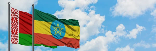 Bandera de Bielorrusia y Etiopía ondeando en el viento contra el cielo azul nublado blanco juntos. Concepto diplomático, relaciones internacionales . — Foto de Stock