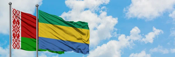 Vitryssland och Gabon flagga vifta i vinden mot vit grumlig blå himmel tillsammans. Diplomatisk koncept, internationella relationer. — Stockfoto