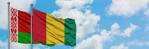 Bandera de Bielorrusia y Guinea ondeando en el viento contra el cielo azul nublado blanco juntos. Concepto diplomático, relaciones internacionales . — Foto de Stock