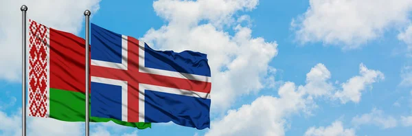 Bandera de Bielorrusia e Islandia ondeando en el viento contra el cielo azul nublado blanco juntos. Concepto diplomático, relaciones internacionales . — Foto de Stock