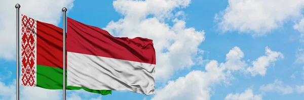 Bandera de Bielorrusia e Indonesia ondeando en el viento contra el cielo azul nublado blanco juntos. Concepto diplomático, relaciones internacionales . — Foto de Stock